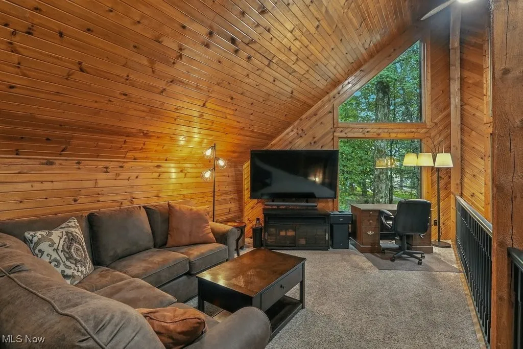 Living area with carpet floors, wood walls, high vaulted ceiling, wooden ceiling, and an office area
