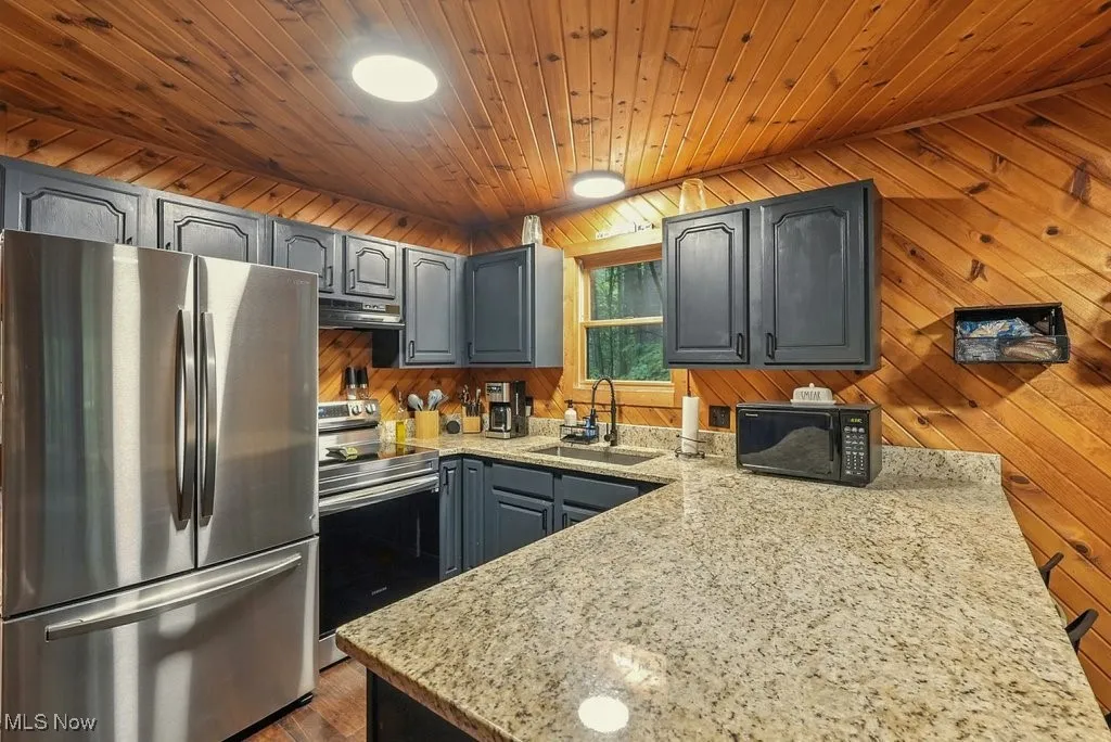 Kitchen featuring stainless steel appliances, gray cabinets, light stone countertops, wooden ceiling, and ventilation hood