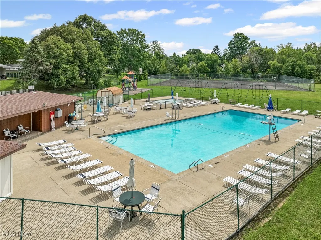 Community pool with a patio area and view of scattered trees