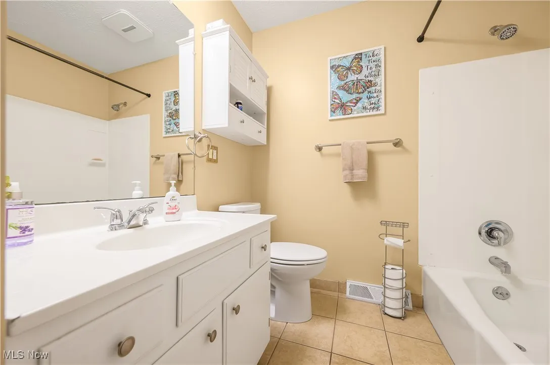 Bathroom featuring shower / bath combination, vanity, and light tile patterned floors
