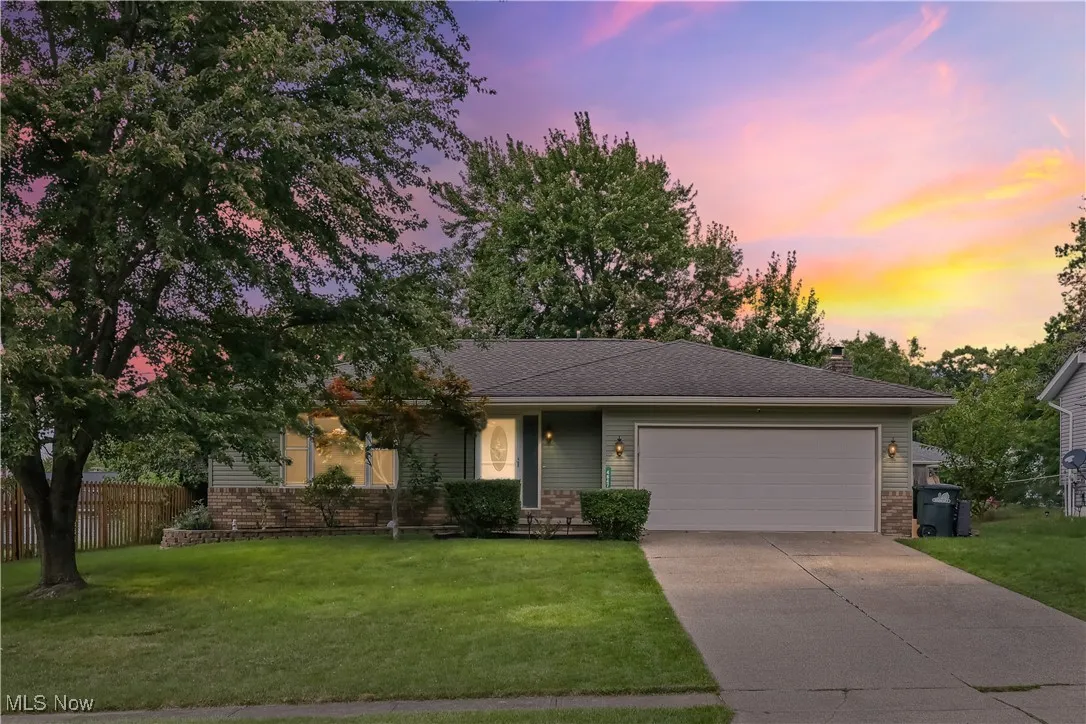 Ranch-style house featuring brick siding, a garage, concrete driveway, and a chimney