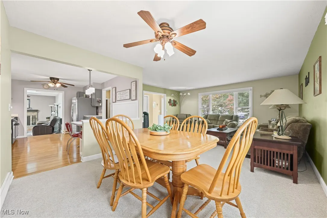 Dining room featuring ceiling fan, light colored carpet, and a fireplace