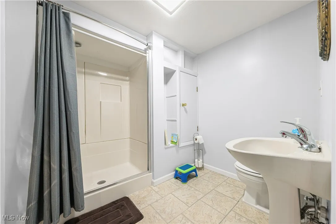 Full bath with a shower stall and baseboards