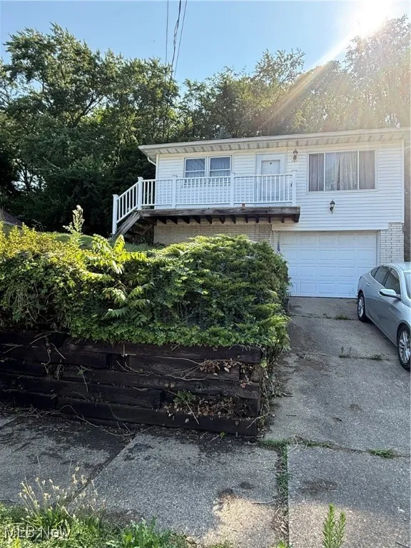 View of front of house featuring driveway, a garage, a balcony, and stairway
