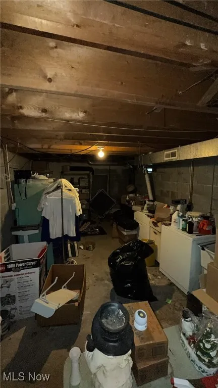Unfinished basement featuring washing machine and clothes dryer