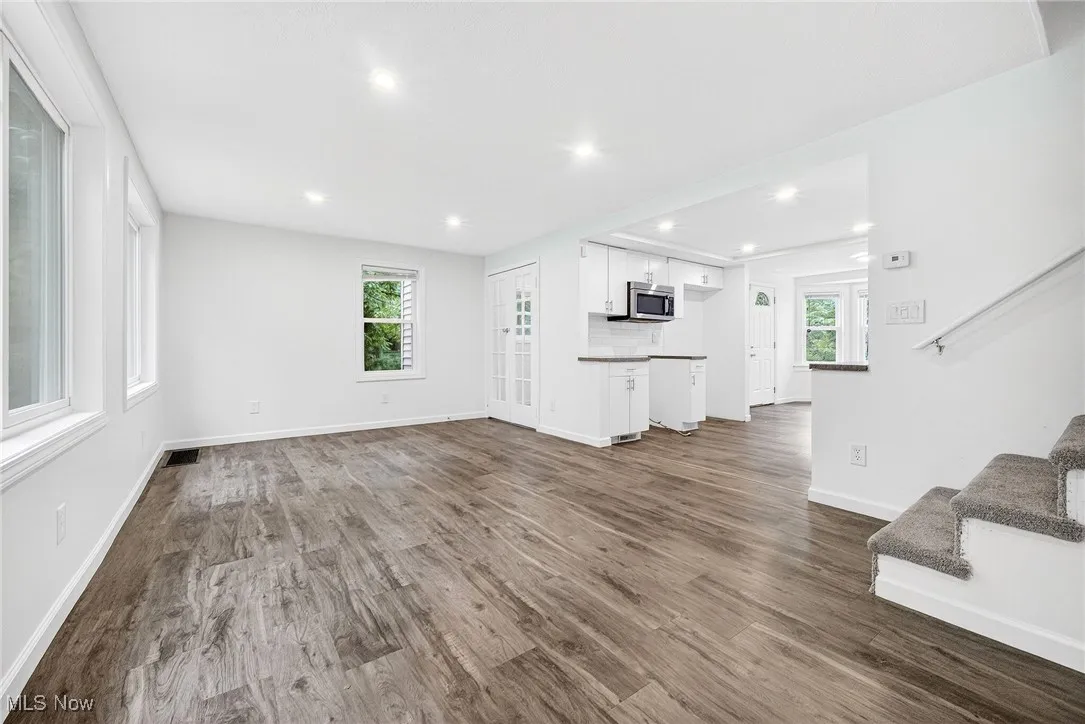 Unfurnished living room featuring stairway, dark wood-style floors, and recessed lighting