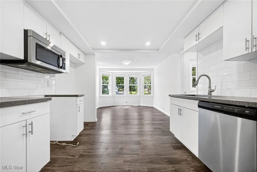 Kitchen featuring tasteful backsplash, stainless steel appliances, white cabinets, dark wood-style flooring, and recessed lighting