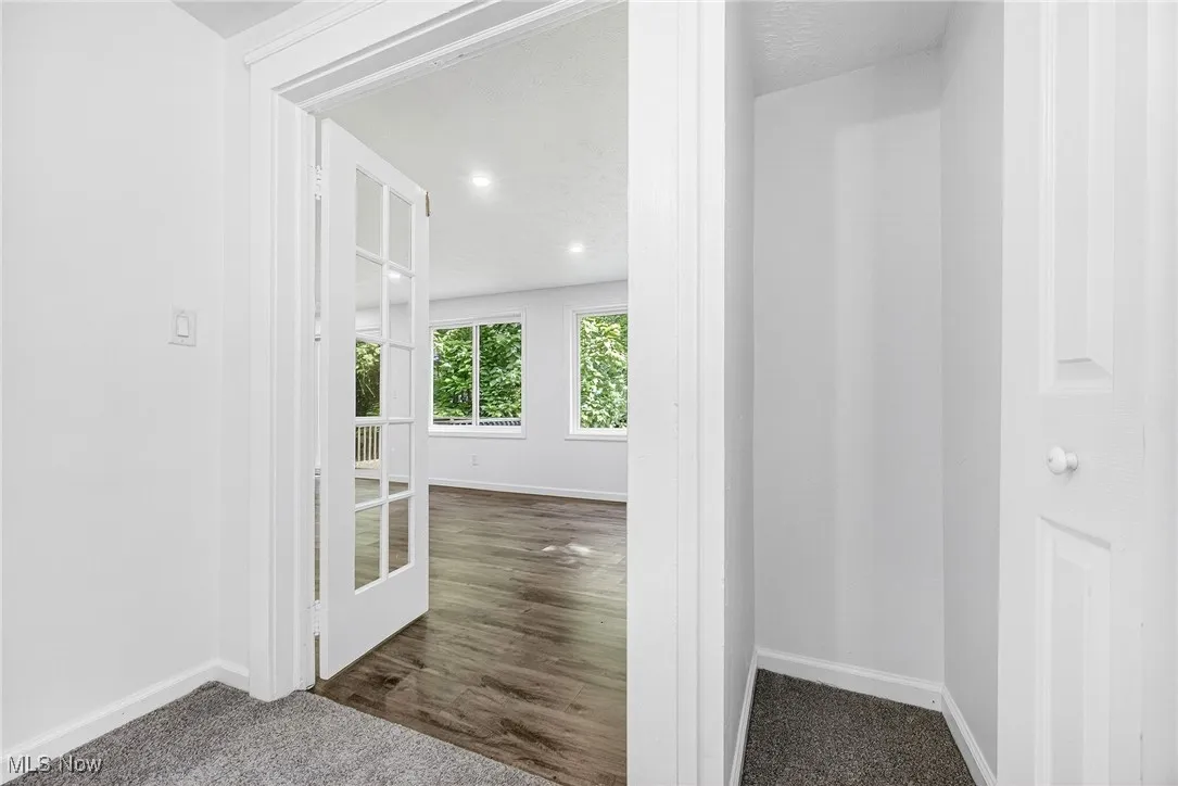 Corridor featuring dark colored carpet and recessed lighting
