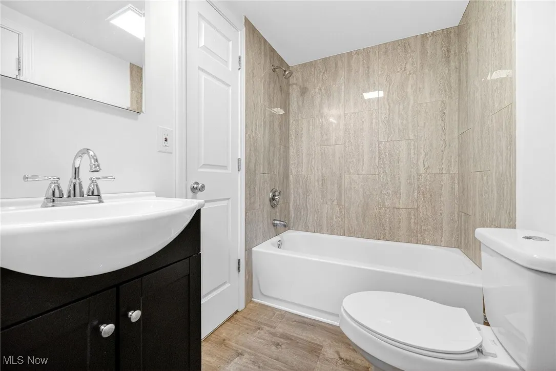 Bathroom featuring shower / tub combination, vanity, and light wood-type flooring