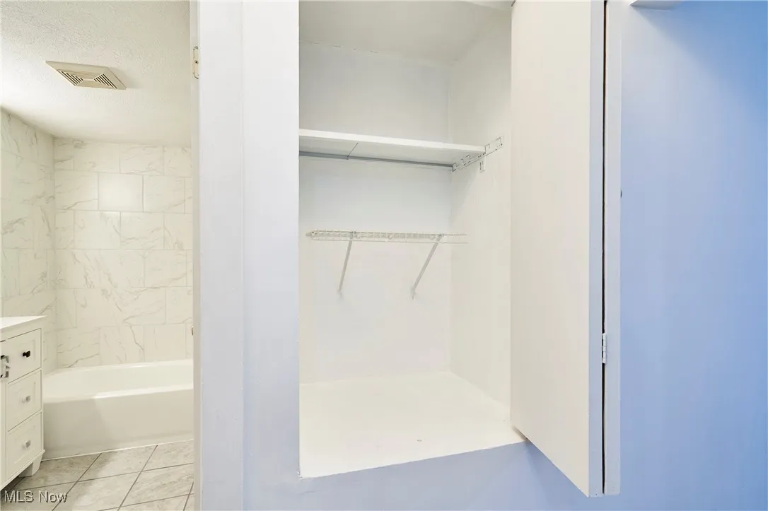 Bathroom featuring vanity, light tile patterned floors, shower / washtub combination, and a closet
