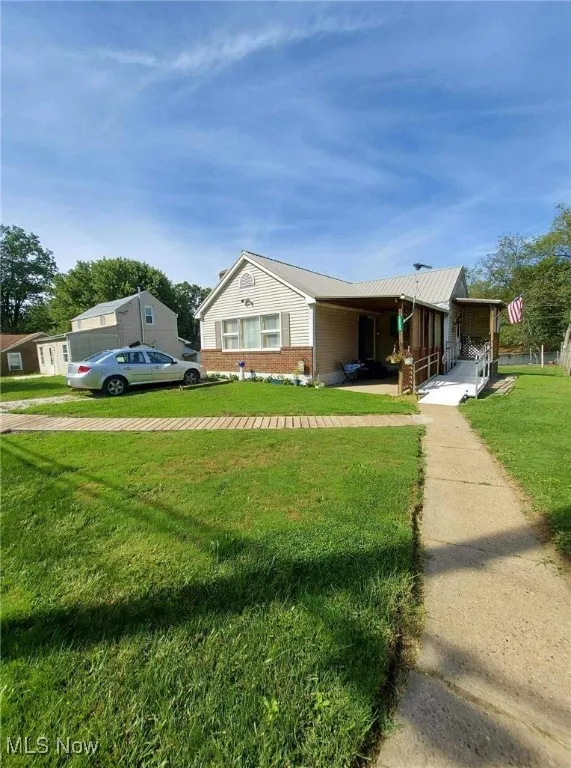 View of front facade featuring a front lawn, a porch, and brick siding