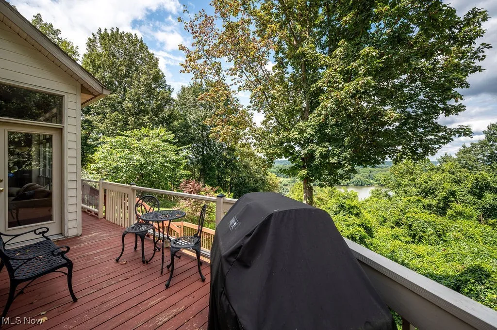 Wooden deck featuring view of scattered trees and area for grilling