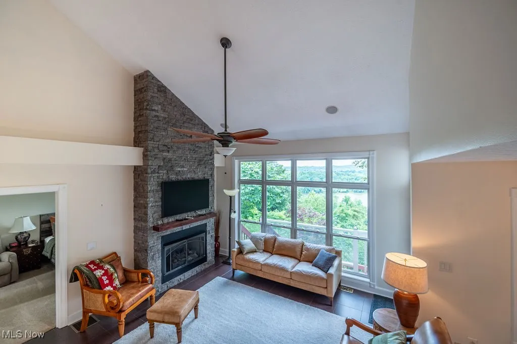 Living room featuring high vaulted ceiling, a fireplace, and a ceiling fan