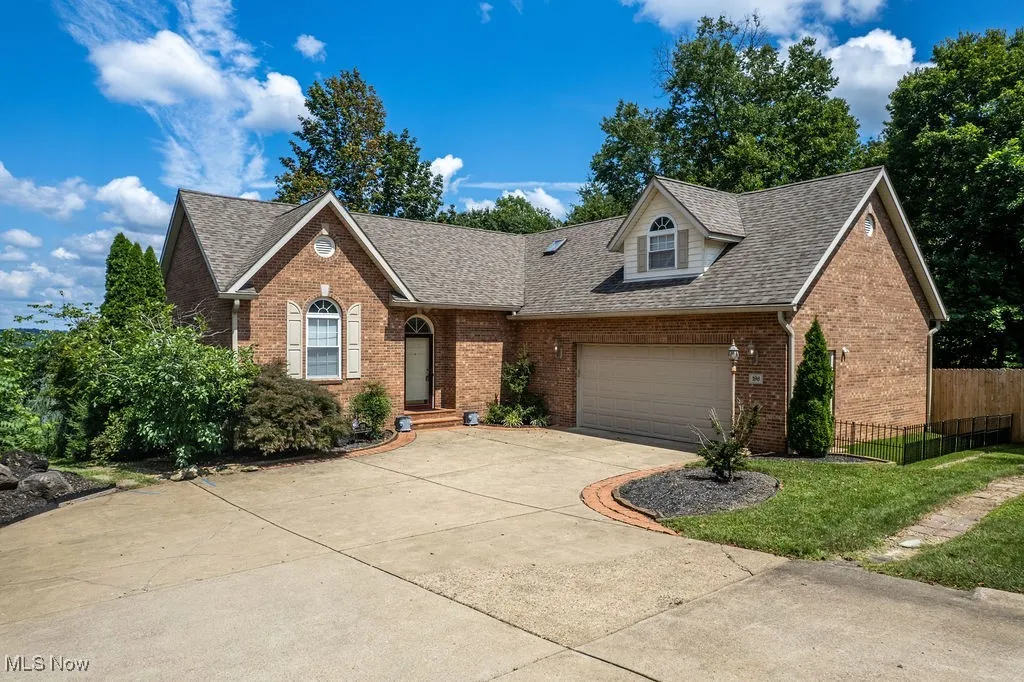 View of front of home with brick siding, driveway, roof with shingles, and an attached garage
