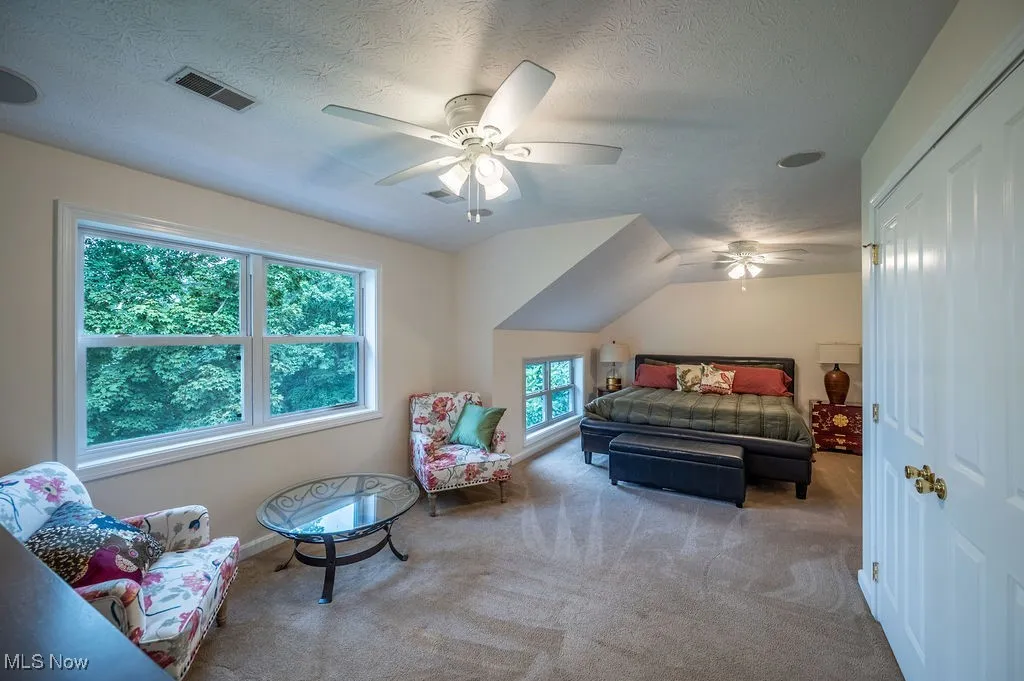 Bedroom with carpet flooring, a ceiling fan, a textured ceiling, and vaulted ceiling