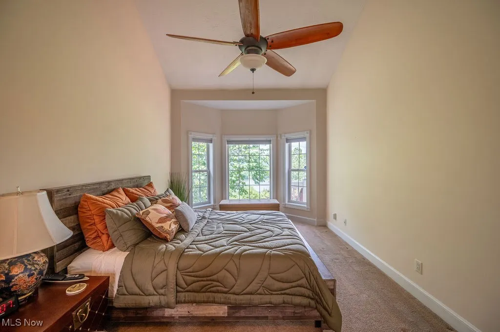 Bedroom with carpet floors, a ceiling fan, and vaulted ceiling
