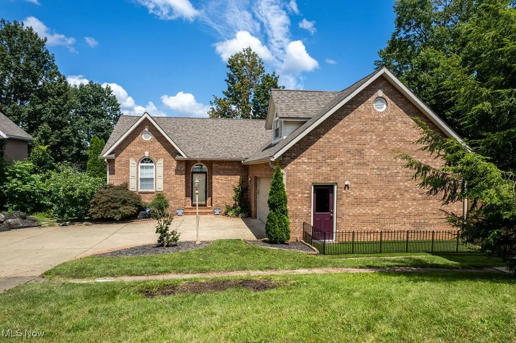 View of front of house featuring concrete driveway, roof with shingles, brick siding, and a garage