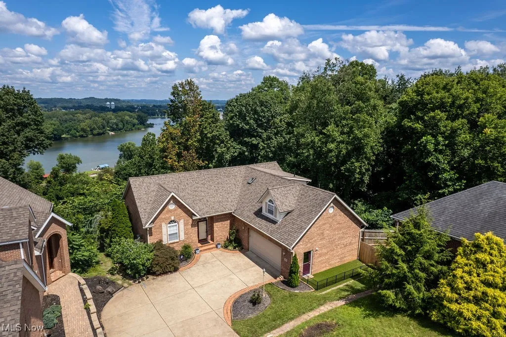 Aerial view of property and surrounding area with a nearby body of water and a heavily wooded area