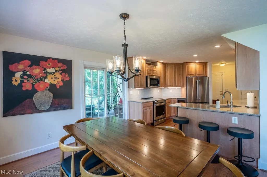 Dining space with a chandelier, light wood finished floors, a textured ceiling, and recessed lighting