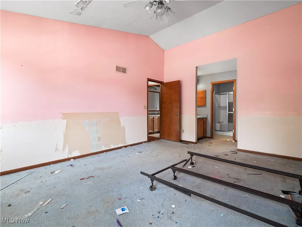 Unfurnished bedroom featuring ensuite bathroom and high vaulted ceiling