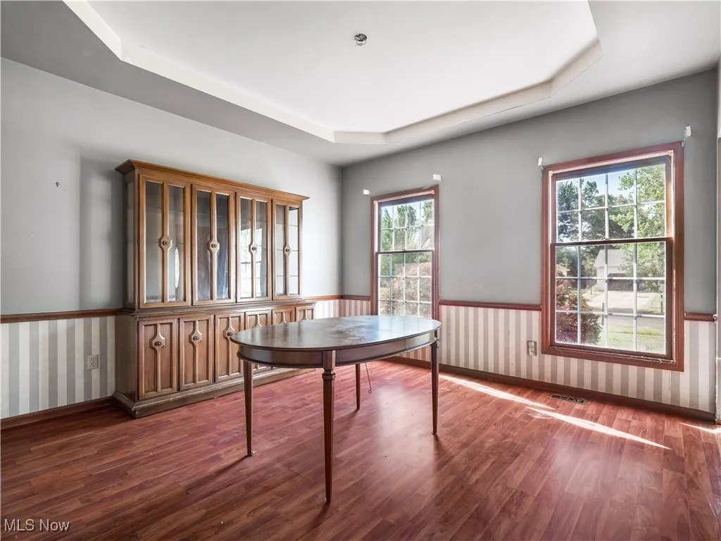 Dining room featuring dark wood-look finished floors and a tray ceiling