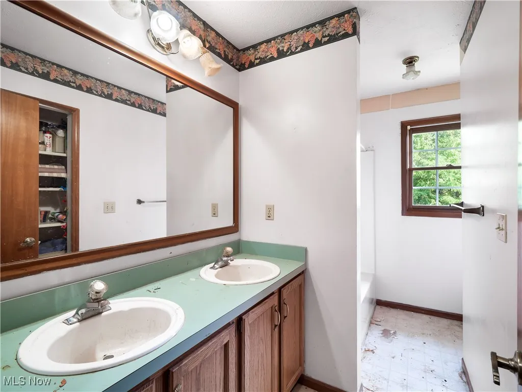 Full bath featuring double vanity, shower / tub combination, and light floors
