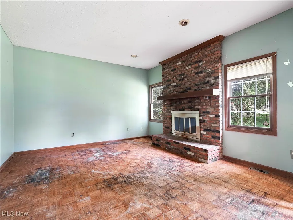 Unfurnished living room with a fireplace and baseboards