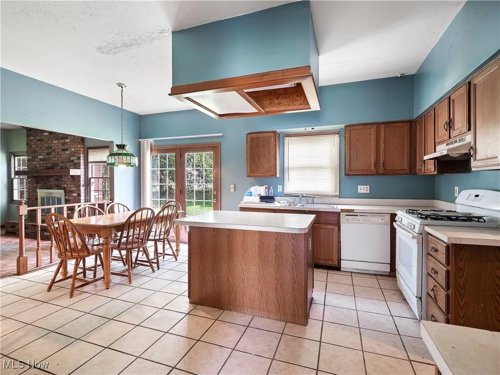 Kitchen with white appliances, hanging light fixtures, brown cabinetry, light countertops, and a textured​​‌​​​​‌​​‌‌​‌‌​​​‌‌​‌​‌​‌​​​‌​​ ceiling
