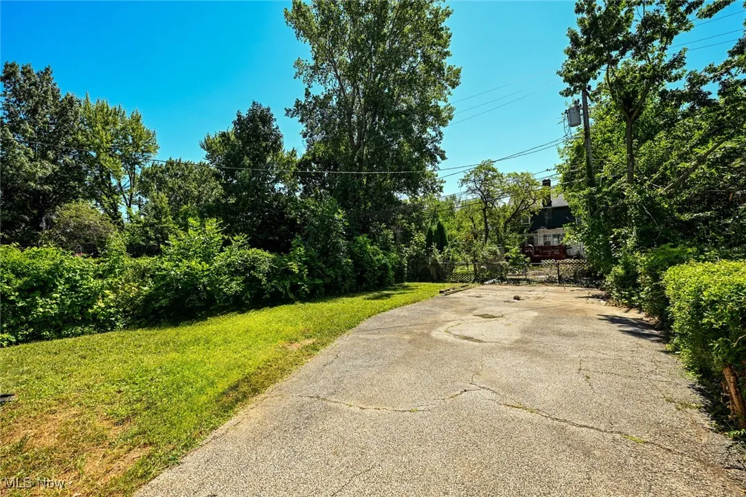 View of asphalt driveway featuring view of wooded area