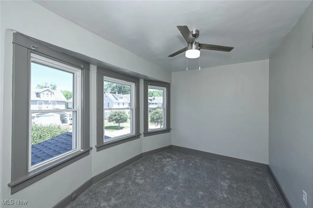 Unfurnished room featuring dark carpet and ceiling fan