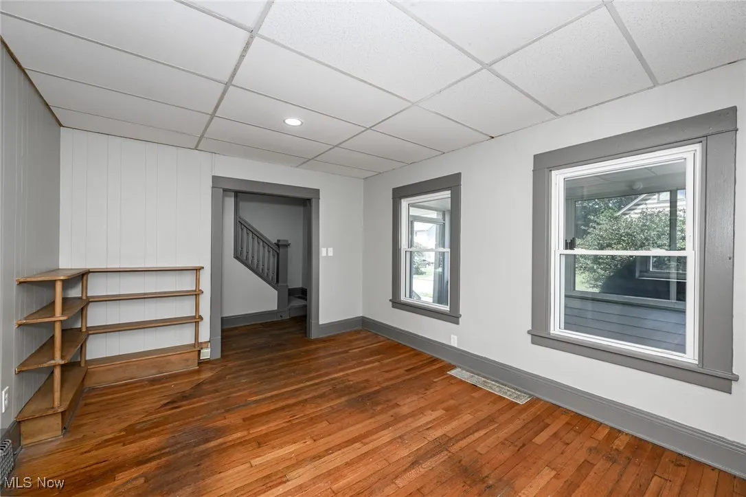Spare room featuring hardwood / wood-style flooring, stairs, and a drop ceiling