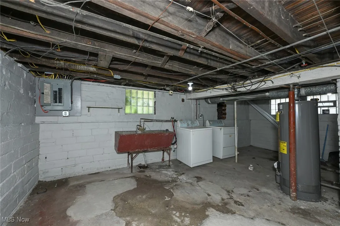 Basement featuring water heater, washer and clothes dryer, and electric panel