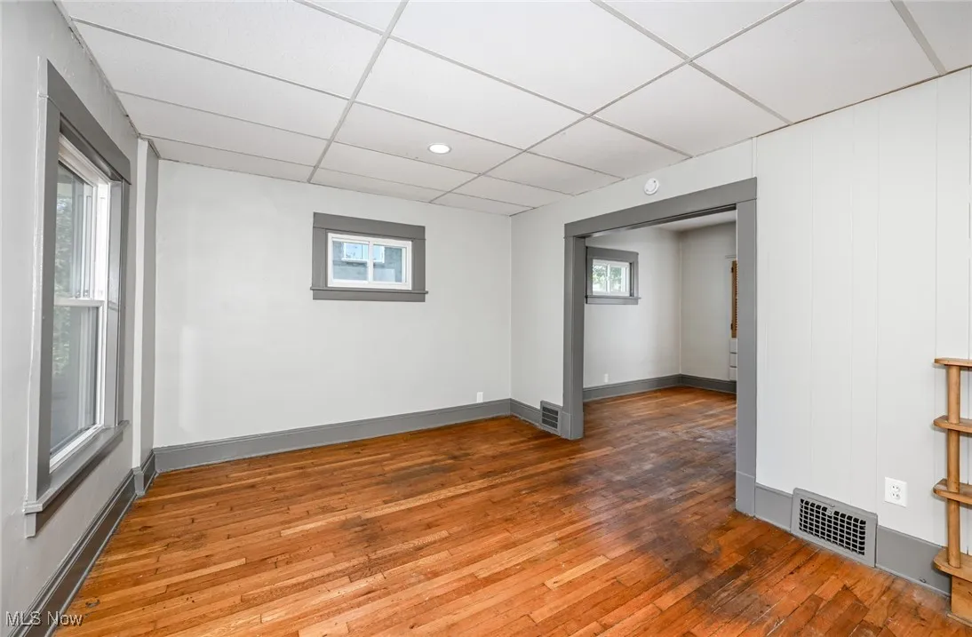 Empty room with light wood-style flooring and a drop ceiling