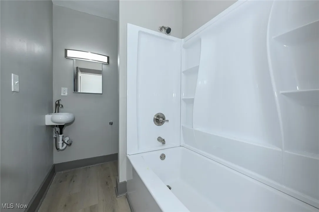 Bathroom with light wood finished floors and shower / bathtub combination