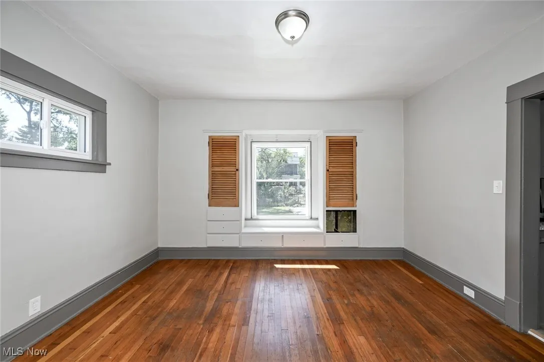Spare room with dark wood-style flooring and baseboards