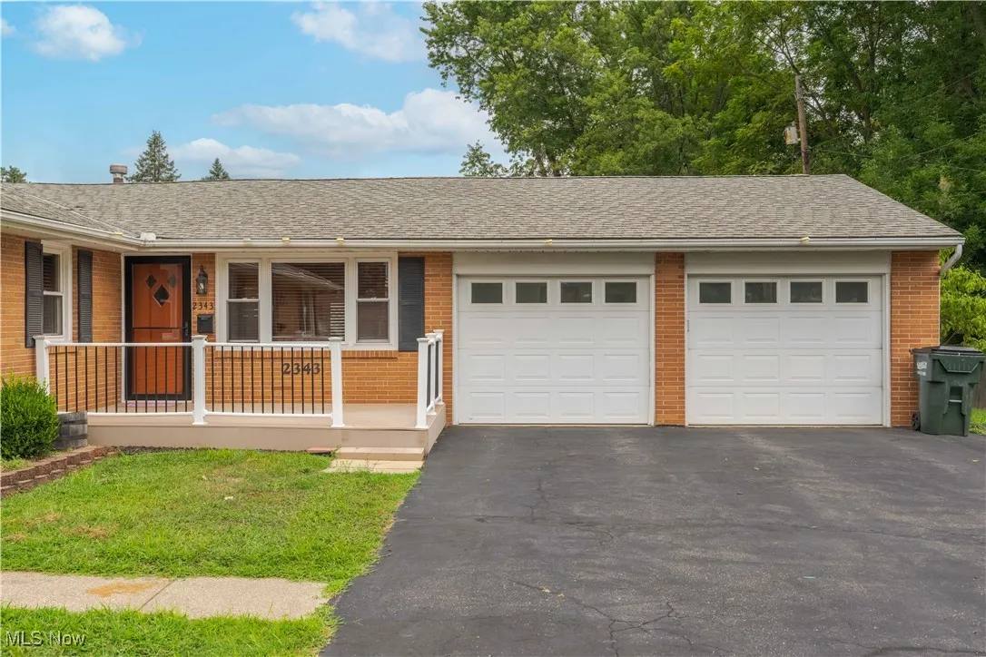 Ranch-style home featuring driveway, brick siding, a shingled roof, an attached garage, and covered porch