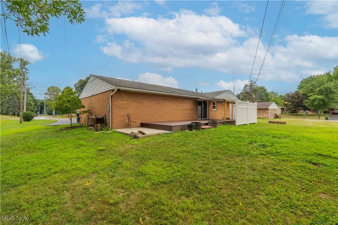 Rear view of house featuring a yard, a deck, and brick siding