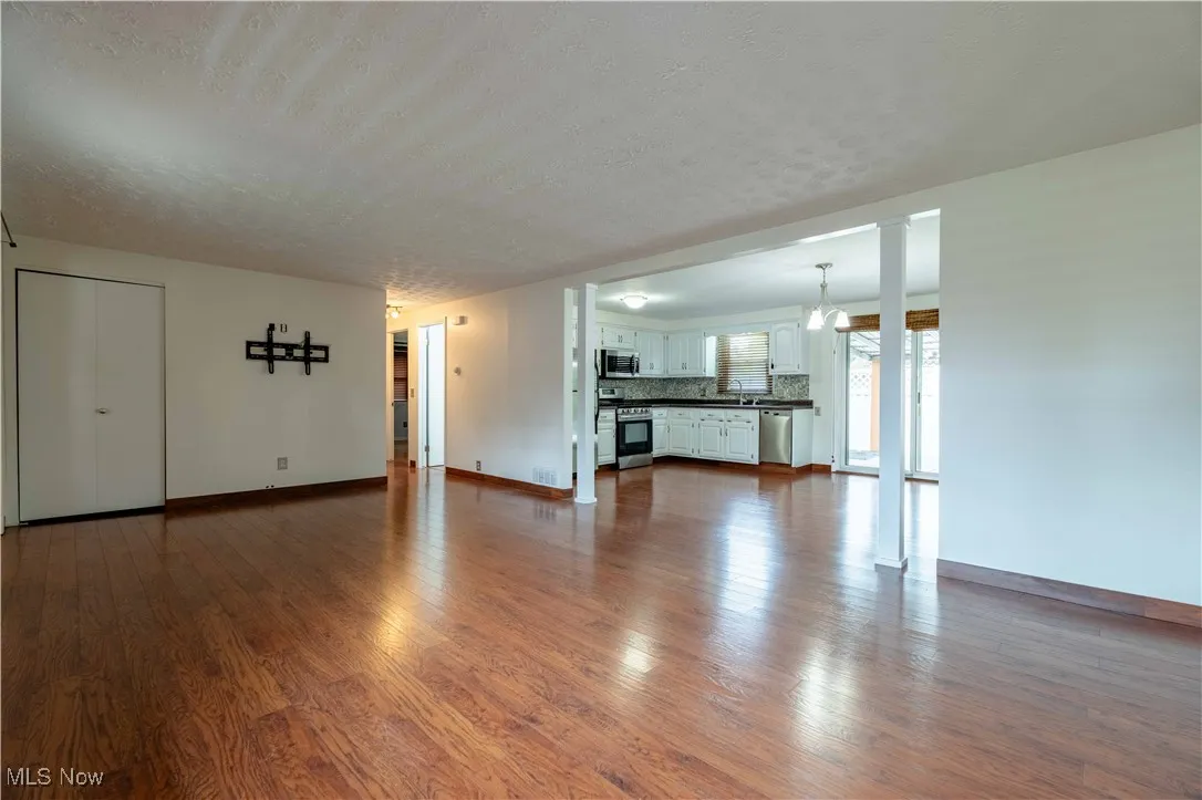 Unfurnished living room featuring dark wood-style flooring and a textured ceiling