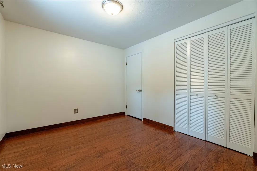 Unfurnished bedroom with dark wood-style floors and a closet