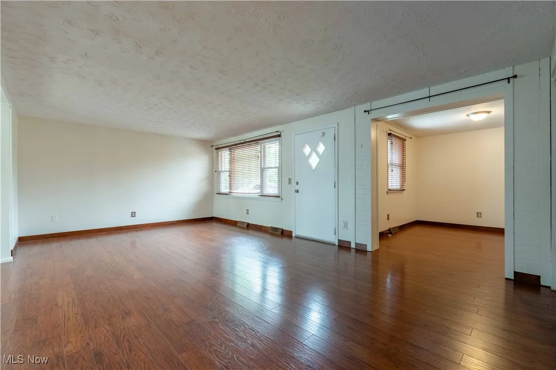 Unfurnished living room with hardwood / wood-style flooring and a textured ceiling