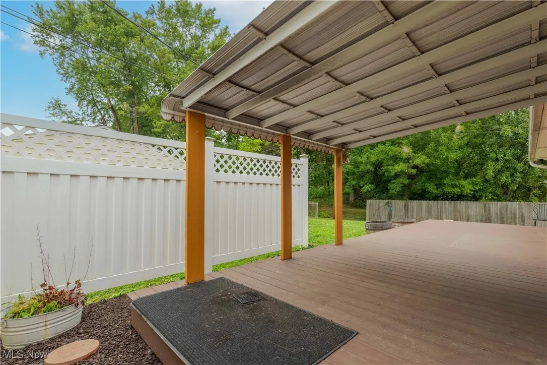 Wooden terrace with a fenced backyard