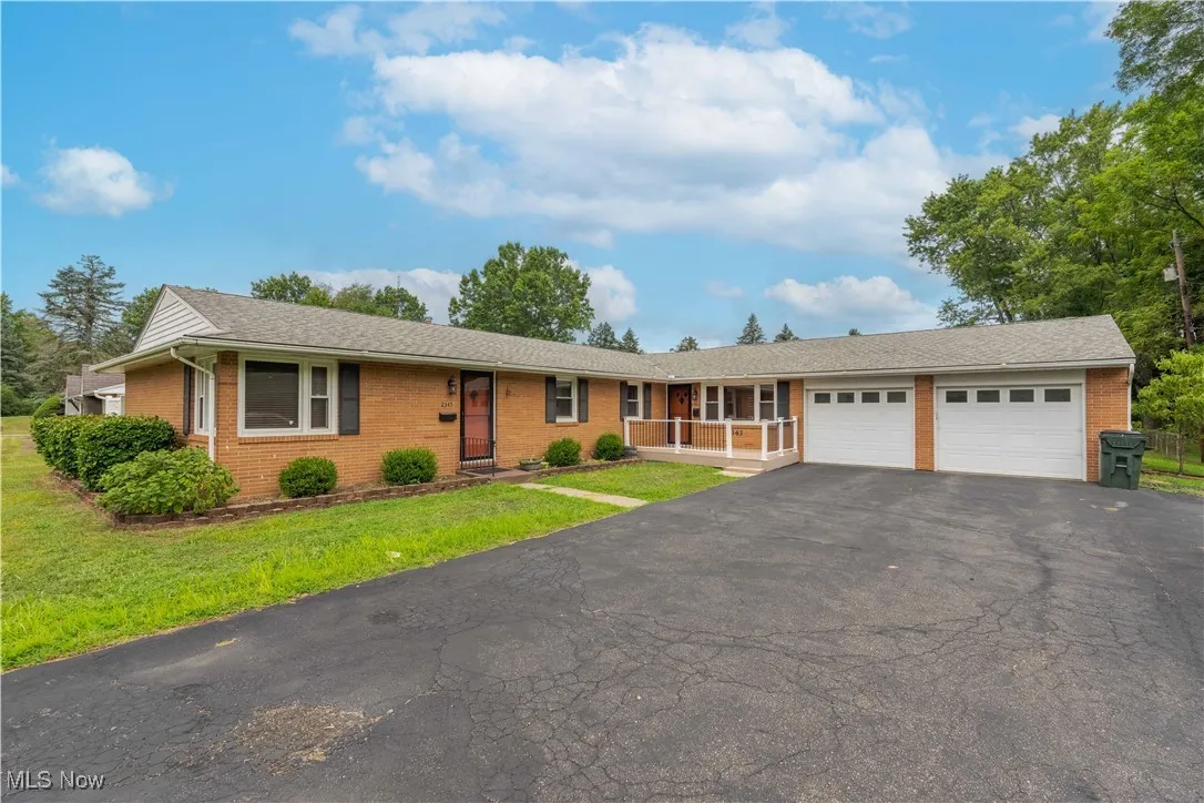 Single story home featuring brick siding, a garage, driveway, a front lawn, and roof with shingles