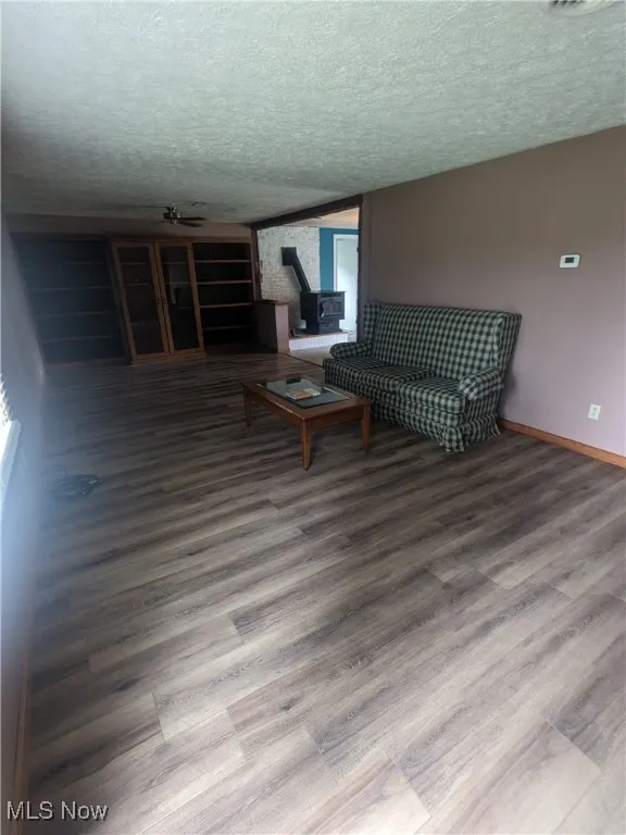 Living area with vinyl plank floors, a textured ceiling,and built-in bookcases.
