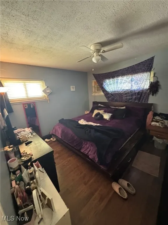 Bedroom featuring a textured ceiling, dark wood-style floors, and ceiling fan