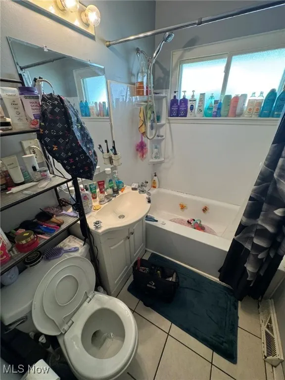 Bathroom featuring shower / tub combo, light tile patterned floors, and vanity