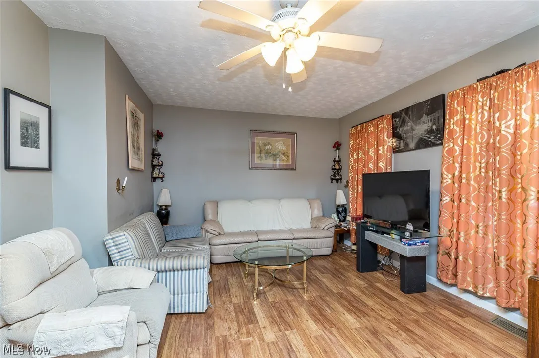 Living area featuring wood finished floors, a textured ceiling, and a ceiling fan