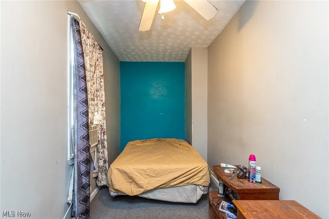 Bedroom featuring a textured ceiling, carpet floors, and ceiling fan