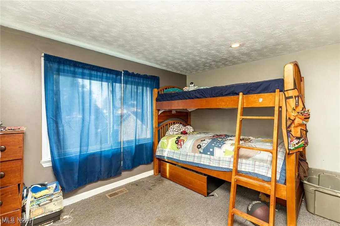 Carpeted bedroom featuring a textured ceiling and baseboards