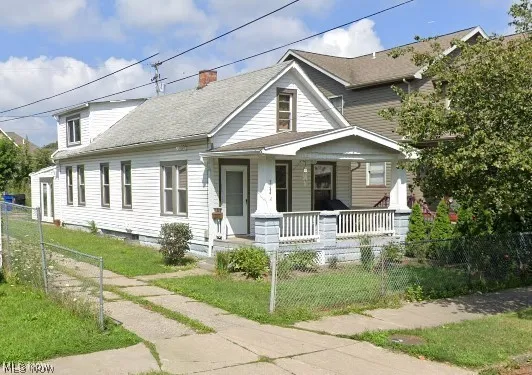 View of front of house with a fenced front yard, a porch, a chimney, and a shingled roof