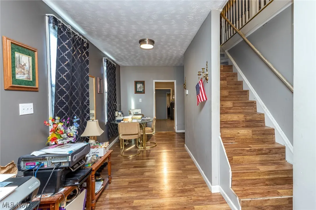 Hall with light wood-type flooring, a textured ceiling, and stairway